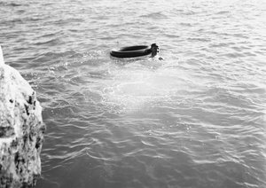 Unidentified man swimming near an inflated inner tube, Hong Kong