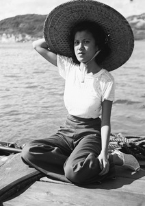 Unidentified woman, wearing a large bamboo hat, on a ferry boat, Hong Kong
