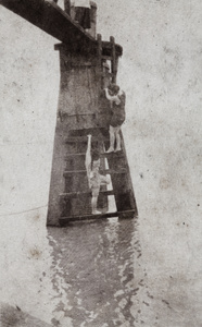 Women in bathing costumes decending the steps of a wooden water pylon