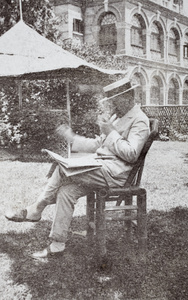W. J. Terrill lighting a pipe while reading a newspaper in his garden, Tongshan Road, Hongkou, Shanghai