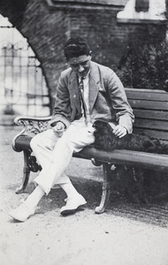 Mr Carrington on a garden bench, with a Pekingese dog