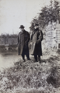 Charles and Bill Hutchinson wearing overcoats, standing beside a waterway, Shanghai