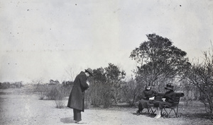 John Piry photographing two young women sitting on a bench, Jessfield Park, Shanghai