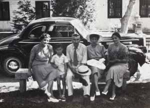 Phyllis Colledge, Roy Hutchinson, John and Maggie Henderson, with Sarah Hutchinson holding a bouquet of flowers, sitting on a bench in front of coupe automobile