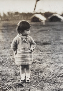 Bea Hutchinson wearing a hand knitted jumper, standing in a park with canvas tents, Shanghai 