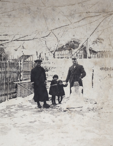 Gardener and unidentified family standing behind a snowman with a bearded mask for a face, Hongkou, Shanghai