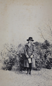 Sarah Hutchinson, holding a camera box, standing in a park, Shanghai