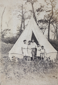 Dick, Maggie and Fred Hutchinson, with John Henderson and an unidentified child, standing outside the entrance to a canvas bell tent, Shanghai