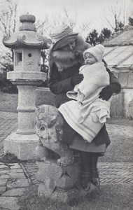 Nellie Thomas sitting on a stone lion holding a blanket-wrapped Bea Hutchinson, Jessfield Park, Shanghai