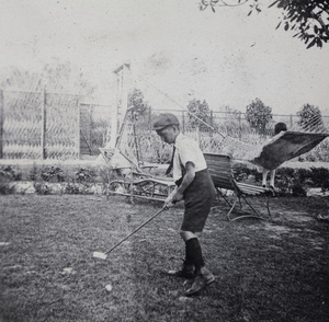 Fred Hutchinson playing with a make-shift golf club in the garden, 35 Tongshan Road, Hongkou, Shanghai