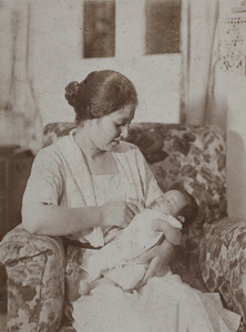 Sarah Hutchinson cradling baby Bea in her arm, sitting in armchair in the living room, 35 Tongshan Road, Hongkou, Shanghai