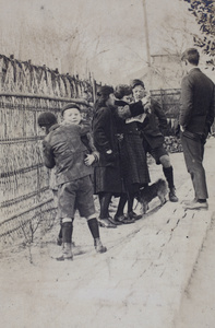 Fred Hutchinson play-fighting with neigbouring boy, while Maggie and Dick Hutchinson read an illustrated newspaper with Mabel Parker, as Harry Hutchinson looks on, 35 Tongshan Road, Hongkou, Shanghai