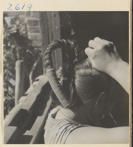 Woman doing her hair in the traditional teapot style in the Lost Tribe country