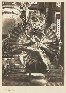 Statue of an animal-headed shrine figure with multiple heads and arms embracing his consort on a lotus throne