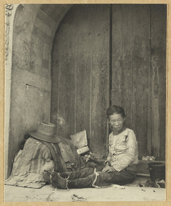 Beggar with possessions sitting in the archway of a gate at Da Fo si