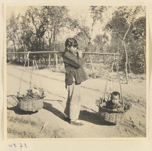Girl carrying produce and a baby in baskets hung from a shoulder pole near Baoding