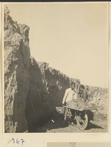 Man pushing a wheelbarrow filled with clay at a brick factory near Baoding