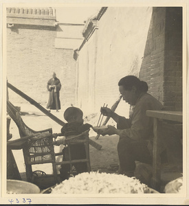 Woman feeding a child in a baby carriage in Baoding