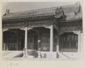 Detail of building facade showing entrance, incense burners on stone pedestals, and metal water vat in the Forbidden City