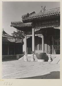 Building with roof ornaments and courtyard with metal water vat and incense burners on stone pedestals in the Forbidden City