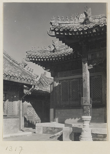 Buildings with roof ornaments and courtyard with incense burner on a stone pedestal in the Forbidden City