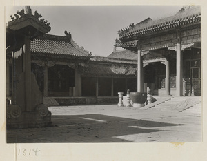 Buildings with roof ornaments and courtyard with bronze water vat and incense burners on stone pedestals in the Forbidden City