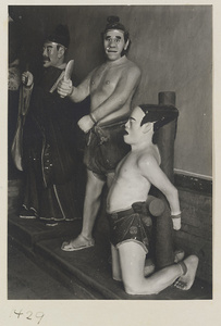 Interior view showing three male figures, one holding a knife, one kneeling and tied to a stake, at Dong yue miao