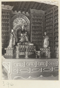 Temple interior showing niche with statues of Buddha and attendants, ritual objects, and walls with Bodhisattva reliefs at Wan shou si