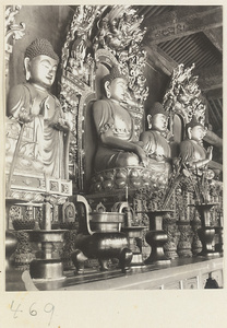 Temple interior showing altar with four Buddha statues and ritual objects at Fa yuan si