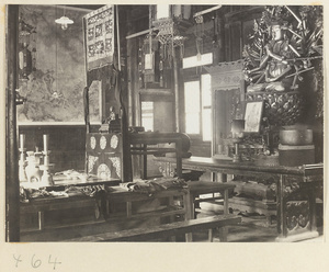 Temple interior showing altar with ritual objects, scroll painting, lanterns, musical instruments, and a multi-armed Bodhisattva at Fa yuan si