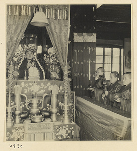 Service with Buddhist nun in headdress behind altar and others playing musical instruments beside altar