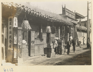 View of shopfronts showing shop signs for a noodle shop (center) and a drum shop (right)