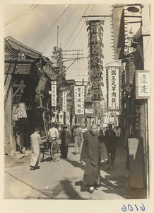 Street scene showing rickshaw puller and shop signs for a noodle shop (left), restaurants (center bottom), and a cigarette shop (center top)