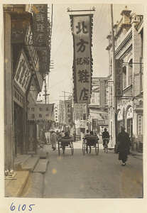 Street scene with a shop sign for a shoe store (center) and rickshaw pullers
