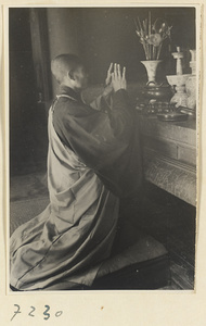 Monk kneeling in front of an altar at Jie tai si