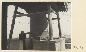 Monk striking a large bell at Jie tai si