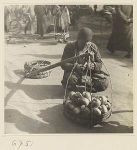 Produce vendor sitting with his wares and shoulder pole