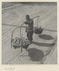 Produce vendor carrying his wares on a shoulder pole