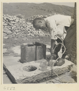 Man pulling a bucket of water from a well with a rope