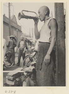 Itinerant knife sharpener blowing a brass instrument called a xiao tong jue or tiao zi to attract customers