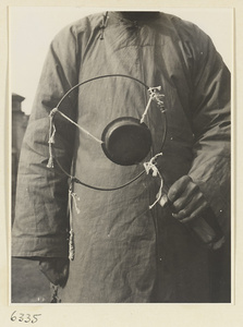 Vendor of sewing supplies holding a gong called a yun luo or ling zi