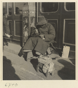 Street vendor sitting and writing next to wares and sign