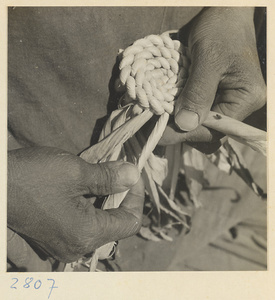 Woman braiding a maize straw cushion