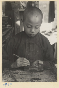 Boy carving lacquer in a workshop