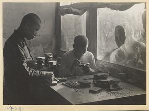 Two men carving lacquer in a workshop