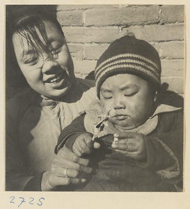 Woman and child with a piece of molded candy on a bamboo stick