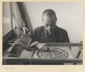 Man embroidering silk in a frame