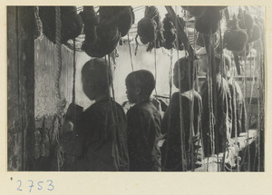Four boys working at a carpet loom