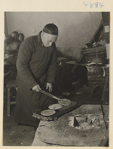 Man working with heated metal plates at a forge in a workshop that makes iron pictures