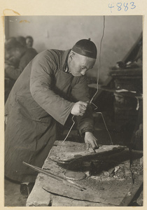 Man working at a forge in a workshop that makes iron pictures